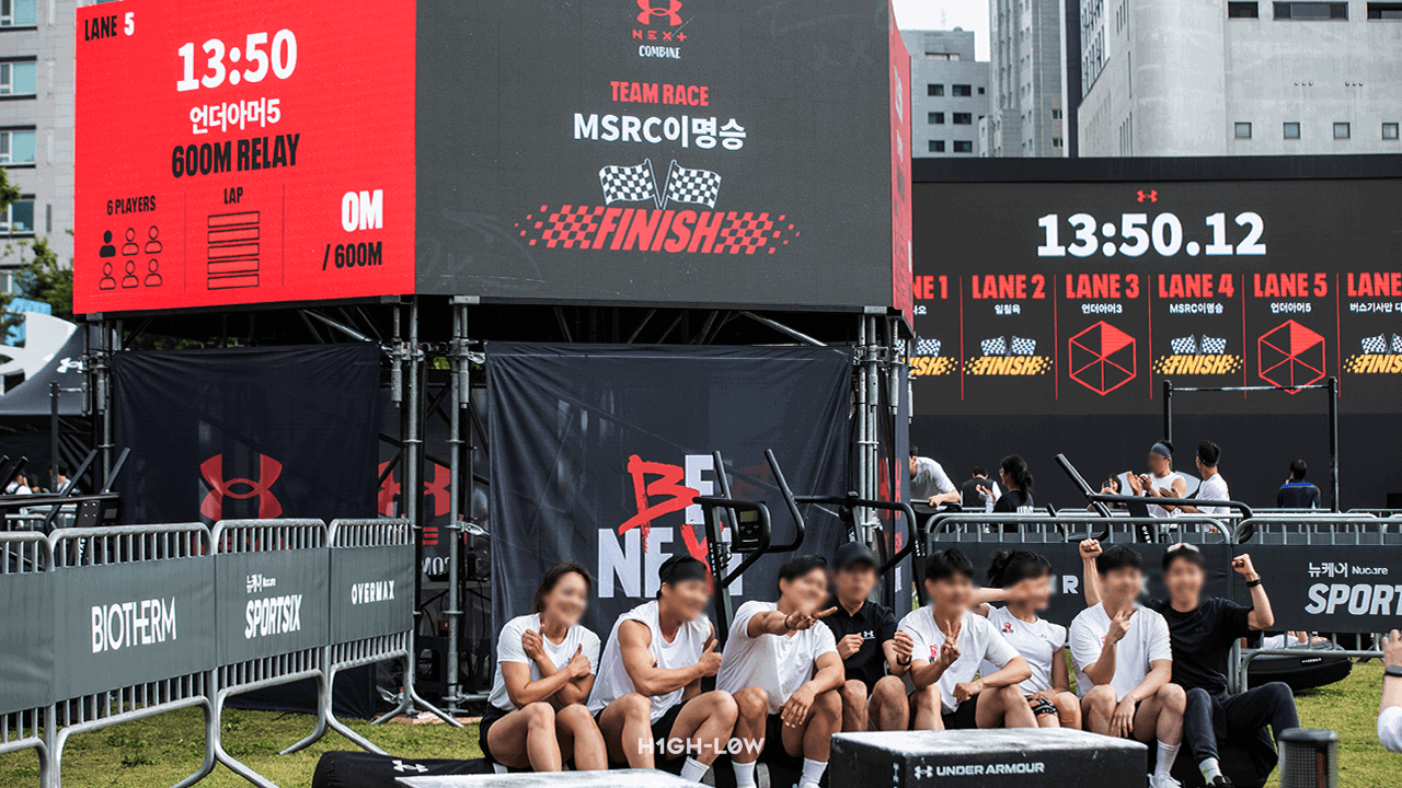 UA NEXT COMBINE 야외 팀 레이스 종목에서 참가자들이 600M RELAY 경기를 마친 후 대형 LED 스코어보드에 실시간 기록이 표시된 모습